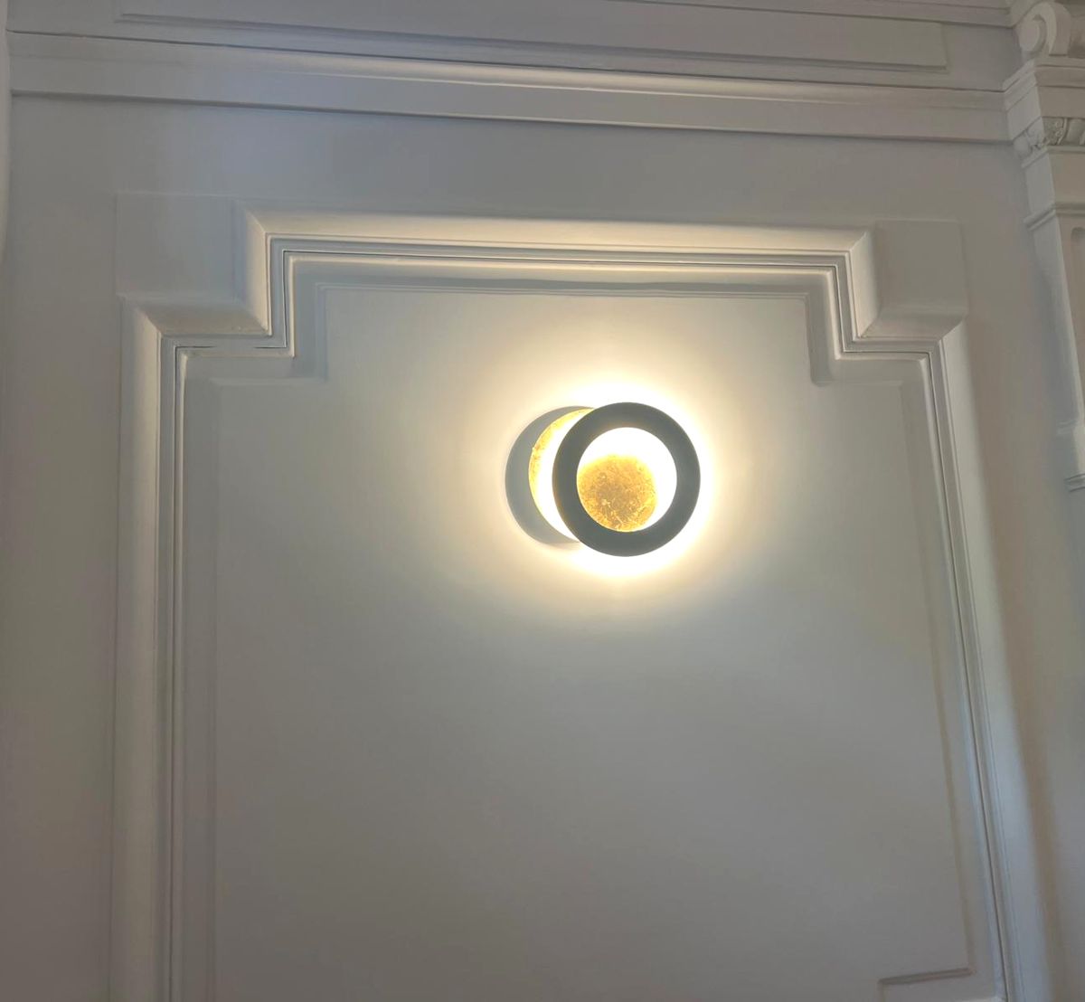 Applique ronde lumineuse sur un mur à moulures